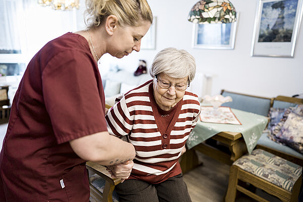 Pflegefachkraft stützt Pflegebedürftige beim Gehen